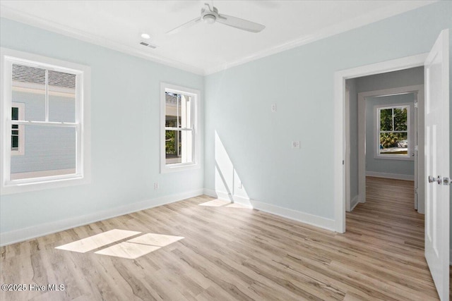 spare room with ornamental molding, a ceiling fan, visible vents, and baseboards