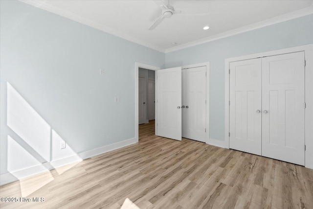 unfurnished bedroom featuring two closets, ornamental molding, baseboards, and light wood finished floors