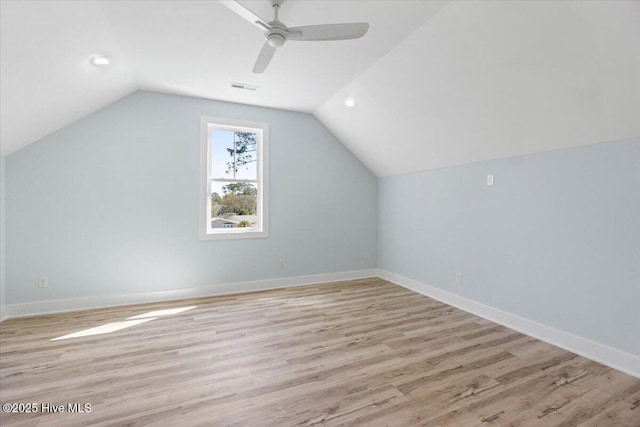 additional living space with visible vents, baseboards, light wood-style floors, and vaulted ceiling