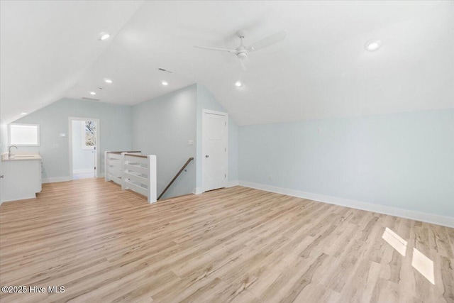 bonus room with a ceiling fan, baseboards, lofted ceiling, and light wood-type flooring