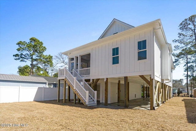 back of house featuring stairway, fence, board and batten siding, a carport, and a patio area