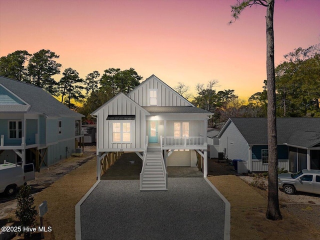 view of front facade featuring driveway, stairway, board and batten siding, covered porch, and a carport