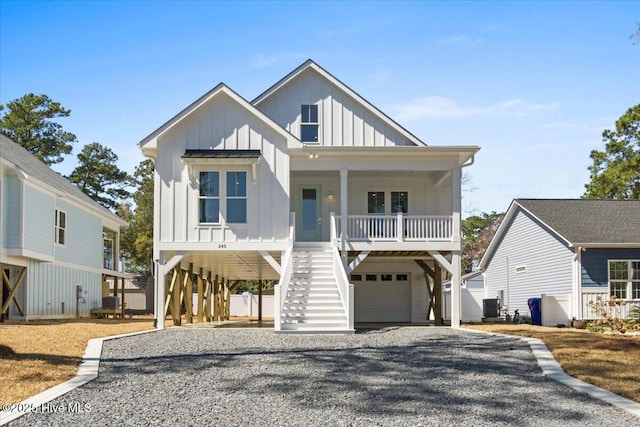 raised beach house with central AC unit, gravel driveway, stairs, board and batten siding, and covered porch