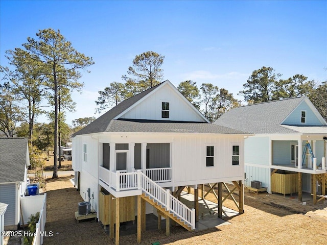 back of property with stairs, a sunroom, and roof with shingles