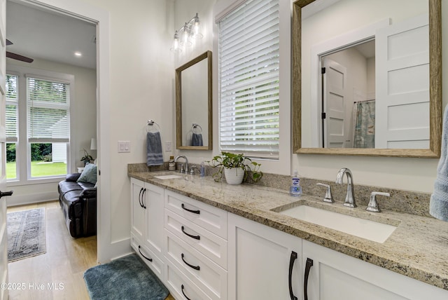 full bath with a sink, an enclosed shower, wood finished floors, and double vanity