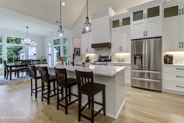 kitchen with decorative backsplash, a breakfast bar area, stainless steel appliances, and an island with sink