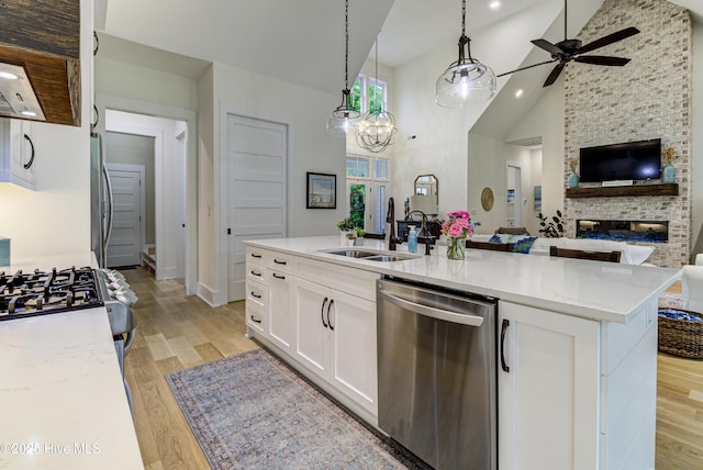 kitchen with light wood-style flooring, a sink, open floor plan, white cabinetry, and appliances with stainless steel finishes