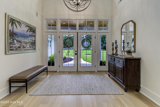 entrance foyer featuring light wood-style flooring, french doors, baseboards, and a towering ceiling