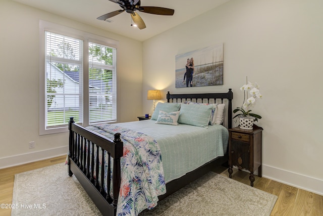 bedroom featuring baseboards, multiple windows, and wood finished floors