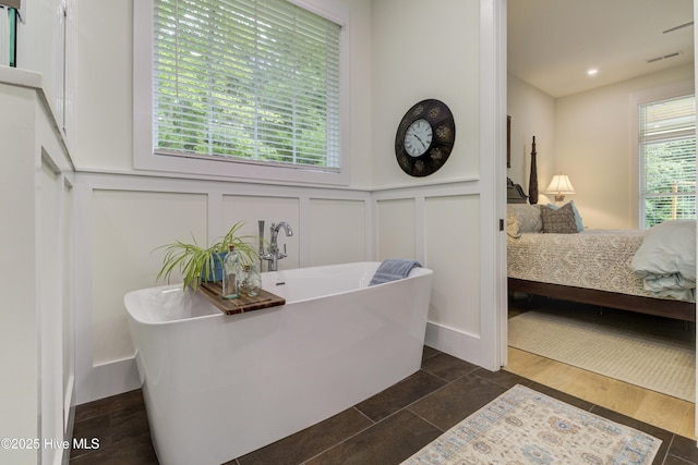 ensuite bathroom with wood finished floors, visible vents, a freestanding bath, a decorative wall, and connected bathroom