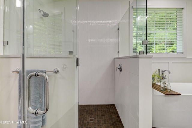 full bathroom featuring a shower stall and a freestanding bath