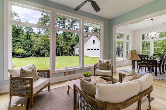 sunroom featuring ceiling fan with notable chandelier