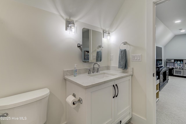 bathroom with vanity, vaulted ceiling, and toilet