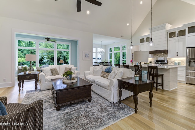 living area featuring recessed lighting, ceiling fan with notable chandelier, light wood-type flooring, and high vaulted ceiling