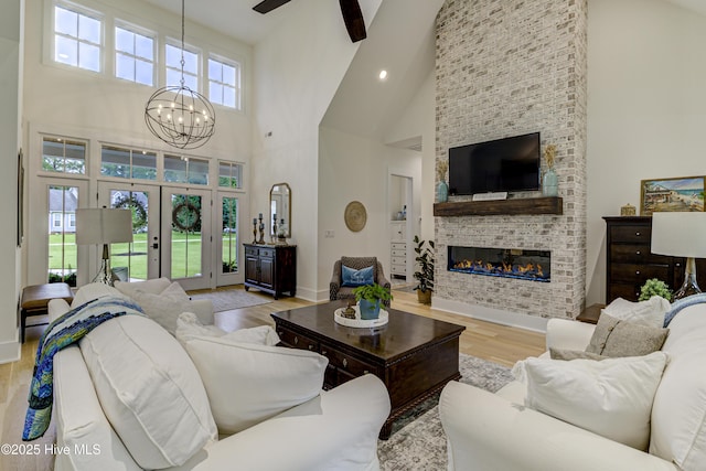 living room with high vaulted ceiling, wood finished floors, french doors, a fireplace, and baseboards