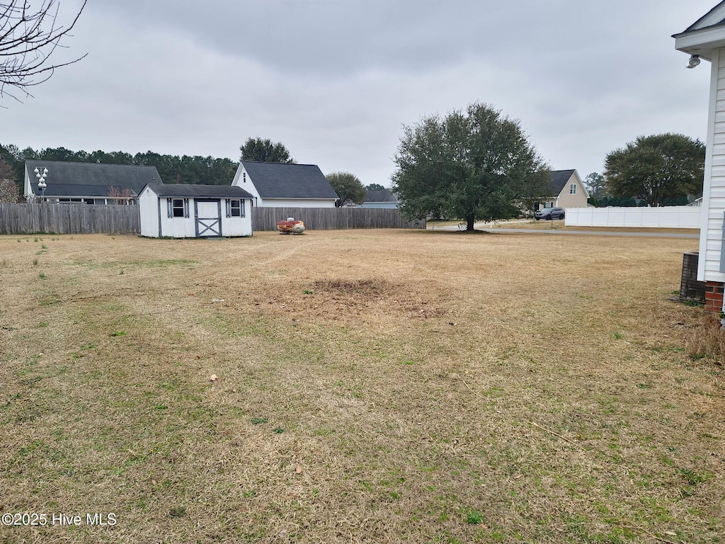 view of yard with an outbuilding, a storage shed, and fence