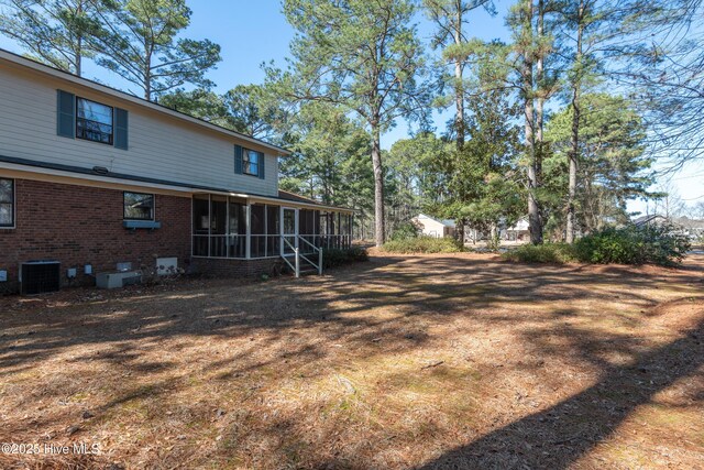 view of yard featuring central AC unit and a sunroom