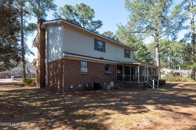 back of house featuring cooling unit, a sunroom, crawl space, brick siding, and a chimney