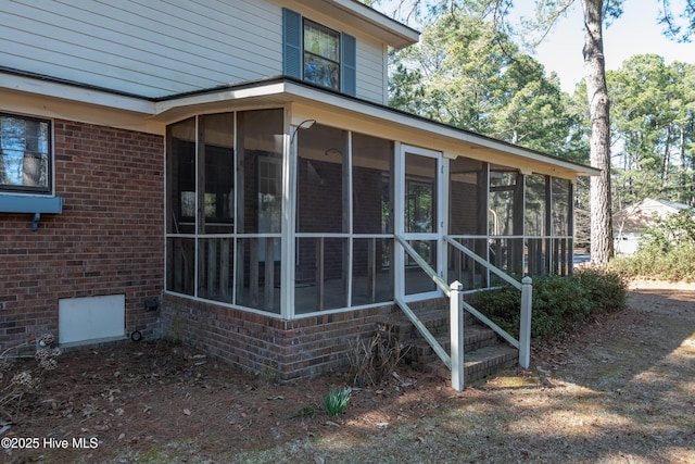 view of side of property with crawl space, brick siding, and a sunroom