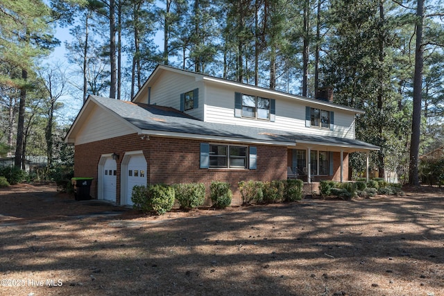 view of front of house featuring a porch, an attached garage, brick siding, and driveway