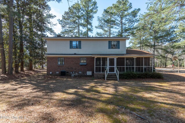 rear view of property featuring cooling unit, brick siding, and a sunroom