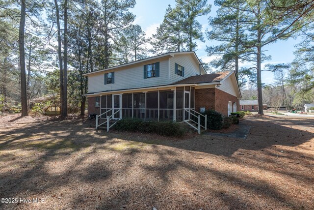 back of house with brick siding and a sunroom