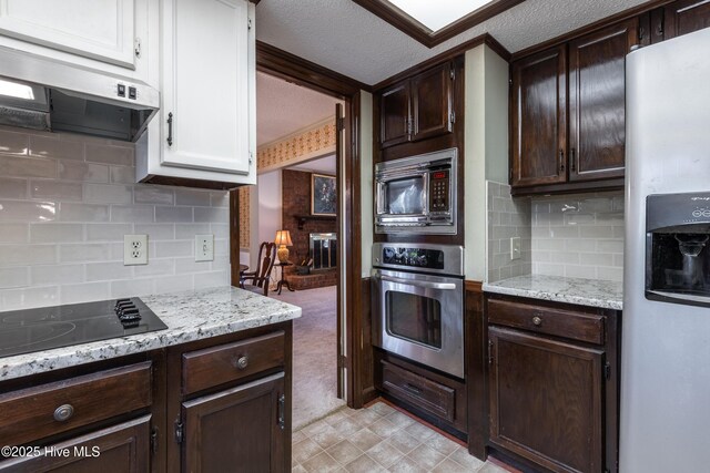 kitchen with a textured ceiling, range hood, dark brown cabinetry, and stainless steel appliances