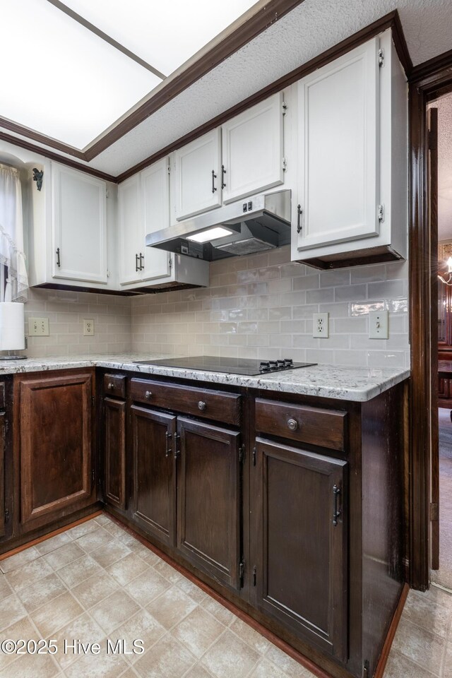 kitchen featuring under cabinet range hood, black electric stovetop, tasteful backsplash, and white cabinetry