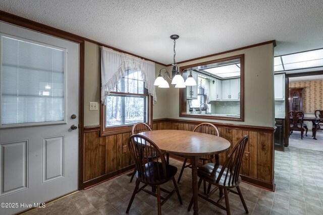 dining space featuring an inviting chandelier, tile patterned floors, a wainscoted wall, and a textured ceiling