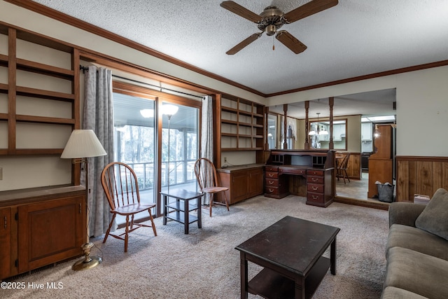 living room featuring built in study area, crown molding, and wainscoting