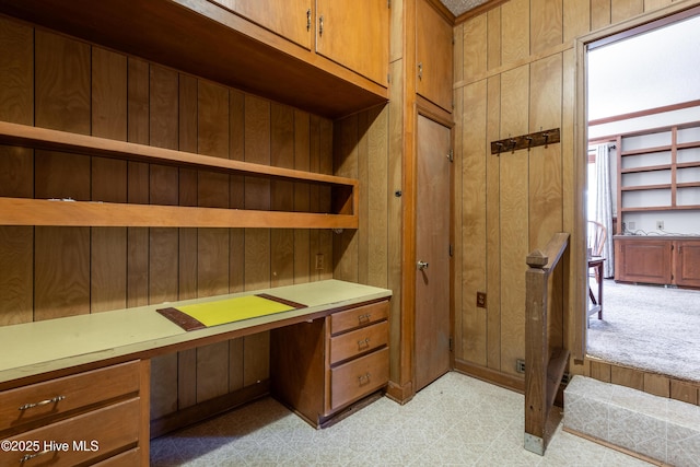 office space featuring built in desk, light floors, and wooden walls