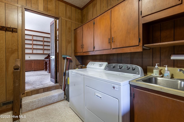 washroom featuring a sink, cabinet space, wooden walls, and independent washer and dryer