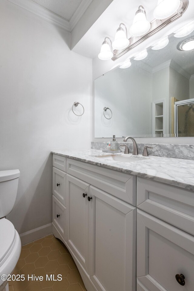 bathroom with vanity, baseboards, crown molding, toilet, and tile patterned floors