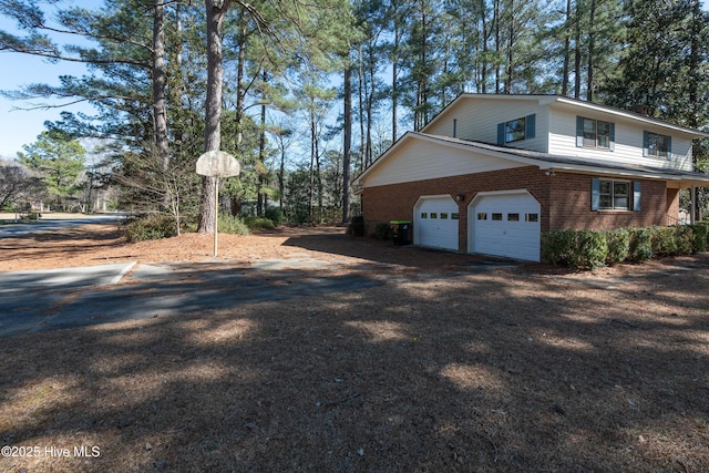 view of property exterior featuring brick siding, driveway, and a garage