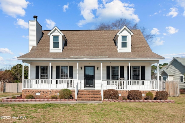 cape cod-style house with a front yard, fence, covered porch, and roof with shingles