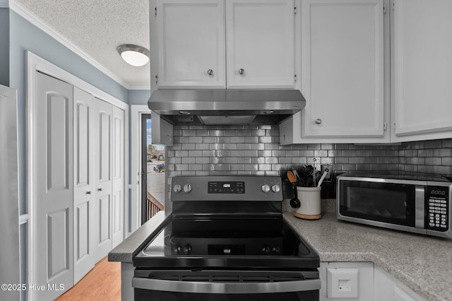 kitchen featuring under cabinet range hood, stainless steel microwave, range with electric stovetop, and white cabinetry