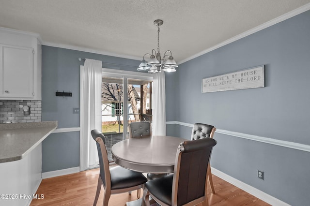 dining space with light wood-style floors, baseboards, a notable chandelier, and ornamental molding