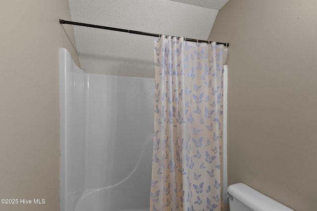 bathroom featuring curtained shower, toilet, and a textured ceiling