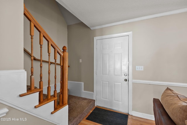 foyer with stairs, wood finished floors, baseboards, and ornamental molding