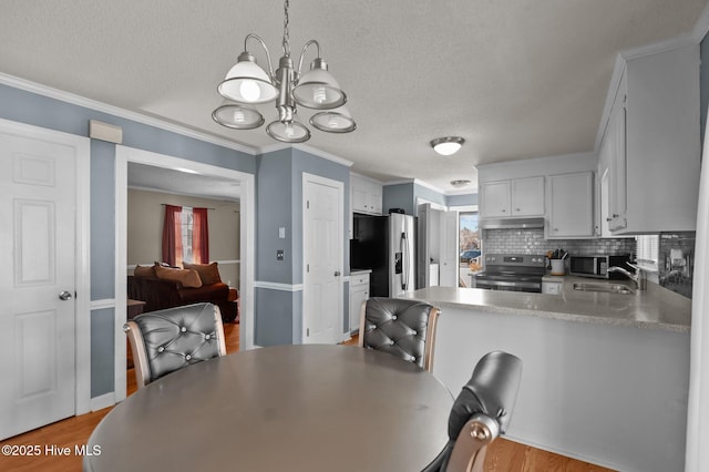 dining area featuring a textured ceiling, a notable chandelier, crown molding, and light wood finished floors