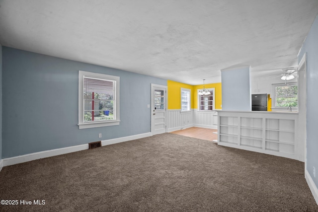 unfurnished living room with visible vents, baseboards, carpet, an inviting chandelier, and a sink