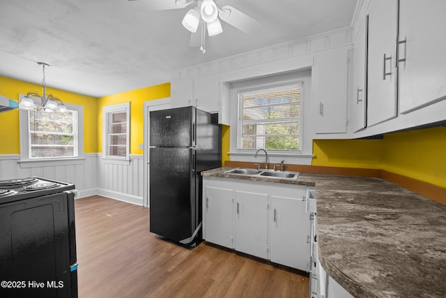 kitchen with dark countertops, black appliances, plenty of natural light, white cabinetry, and a sink