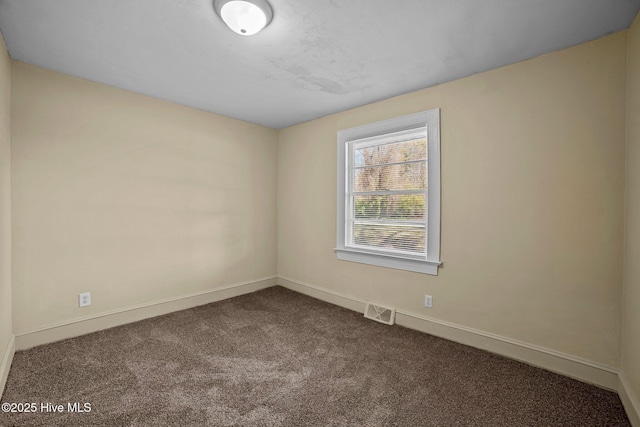 unfurnished room with visible vents, baseboards, and dark colored carpet