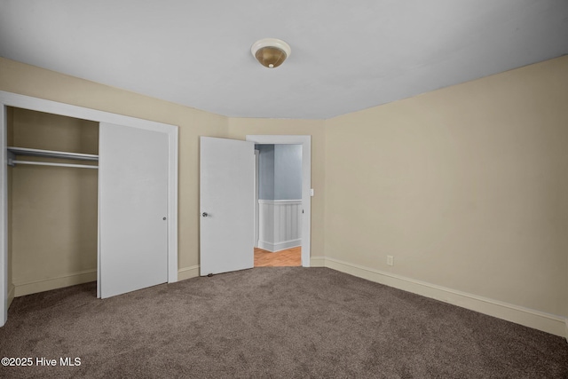 unfurnished bedroom with a closet, carpet flooring, and baseboards