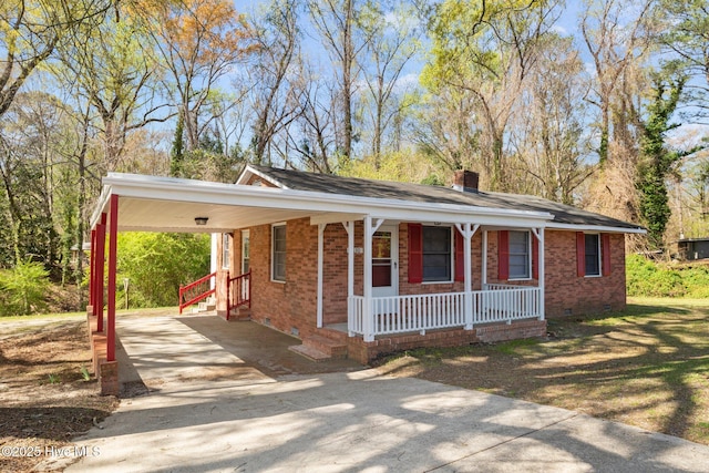 view of front of home featuring crawl space, driveway, a porch, and brick siding