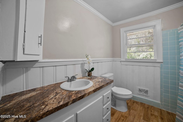 full bath with wood finished floors, visible vents, ornamental molding, wainscoting, and toilet