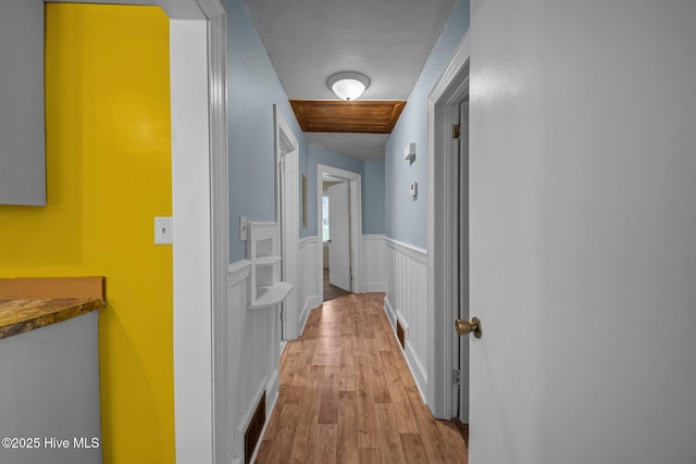 corridor featuring visible vents, wood finished floors, and wainscoting