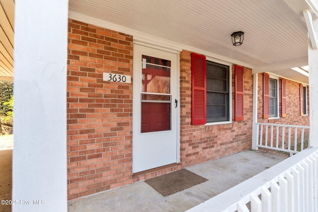 doorway to property with brick siding and covered porch