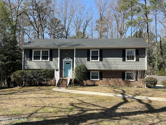 bi-level home with brick siding, a front lawn, and fence