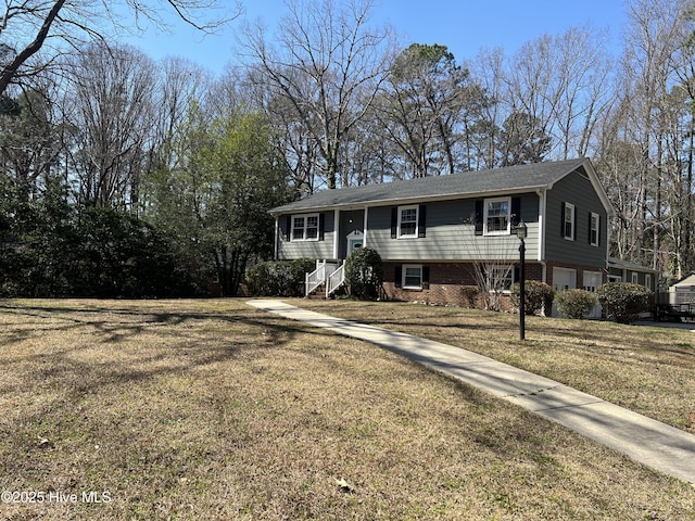 bi-level home with a front yard, a garage, and brick siding